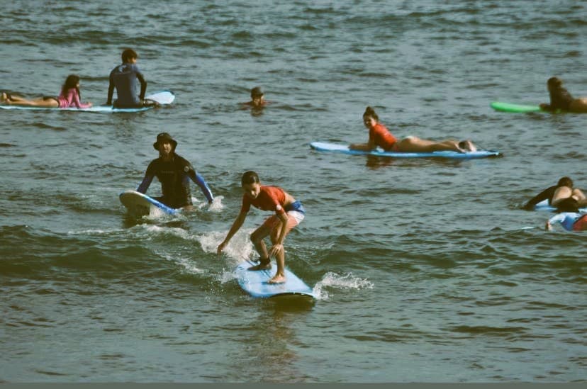 Several students on softboards in the water around Andres